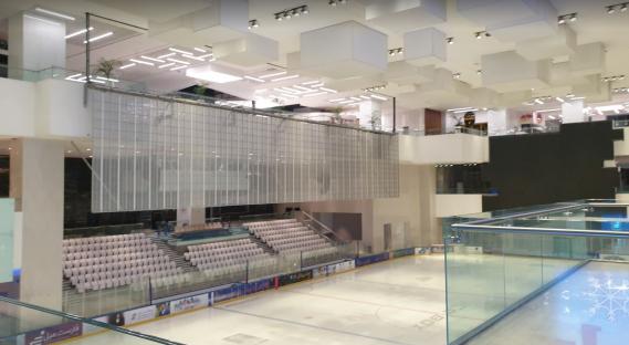 Indoor ice rink with seating area in a mall.