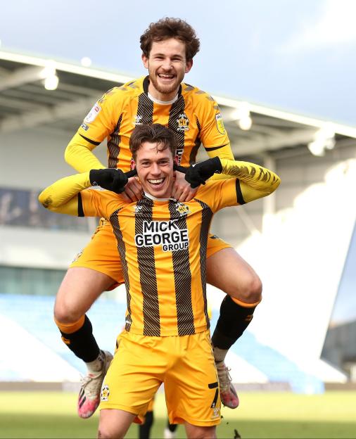 Cambridge United's Luke Hannant (bottom) celebrates scoring their side's fourth goal of the game with team-mate Jack Iredale during the Sky Bet League Two match at Boundary Park, Oldham. PA Photo. Picture date: Saturday March 13, 2021. See PA story SOCCER Oldham. Photo credit should read: Martin Rickett/PA Wire. RESTRICTIONS: EDITORIAL USE ONLY No use with unauthorised audio, video, data, fixture lists, club/league logos or "live" services. Online in-match use limited to 120 images, no video emulation. No use in betting, games or single club/league/player publications.