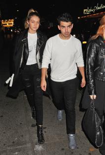 Gigi Hadid and Joe Jonas walking down a city street at night.