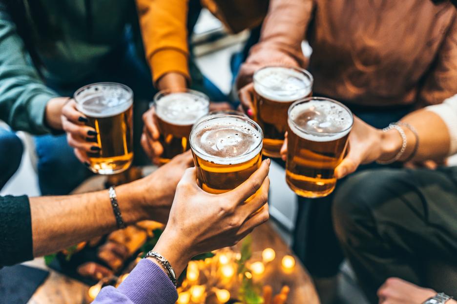 Five people toasting with glasses of beer.