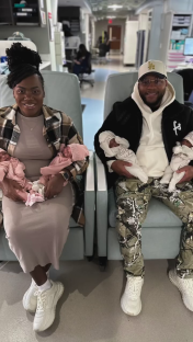 A couple holding their newborn quadruplets in a hospital waiting area.