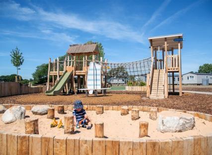 Toddler playing in a sandpit at Mill Rythe Holiday Park playground.