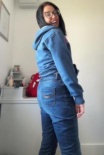 Woman in blue hoodie and jeans smiling and turning.