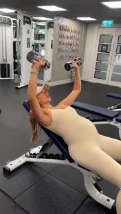 Pregnant woman lifting weights in a gym.