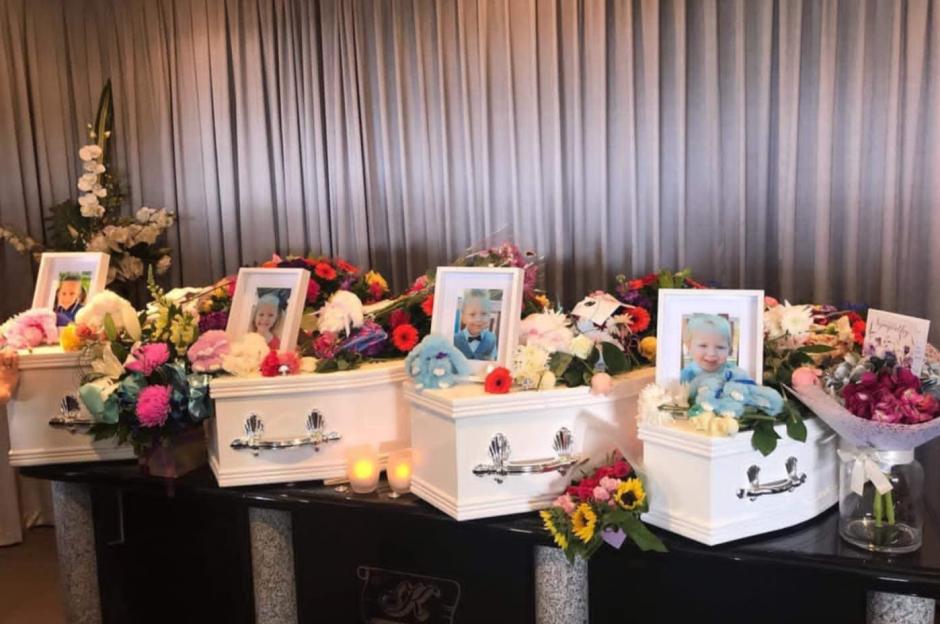 Three white caskets with flowers and photos of children.