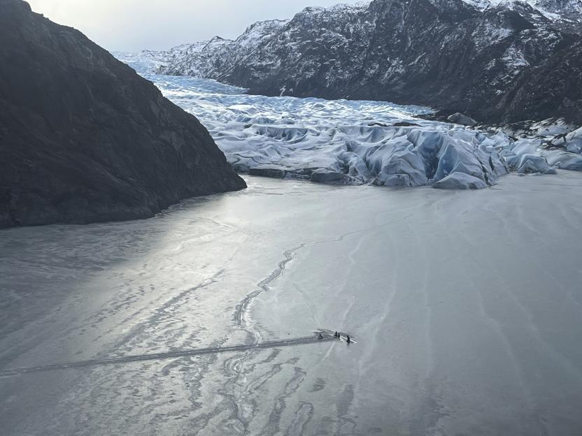 Airplane partially submerged in ice near glacier.