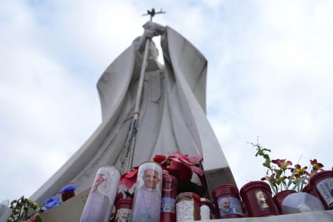 Candles with Pope Francis's image at a statue of Pope John Paul II.