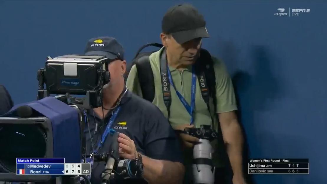 US Open photographer on court during a tennis match.