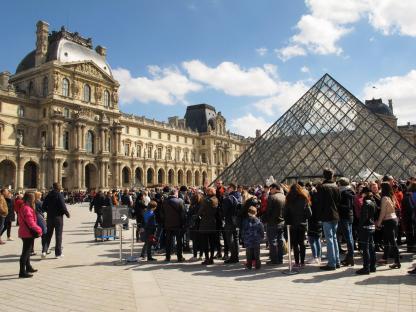 Tourists queuing in front of the Louvre Pyramid in Paris.