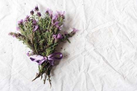Lavender bouquet tied with a purple ribbon on a white tablecloth.