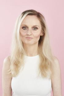 Woman with blonde hair wearing a white top.