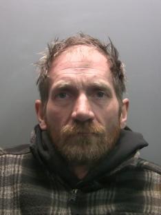 Mugshot of a man with light brown hair and a beard.