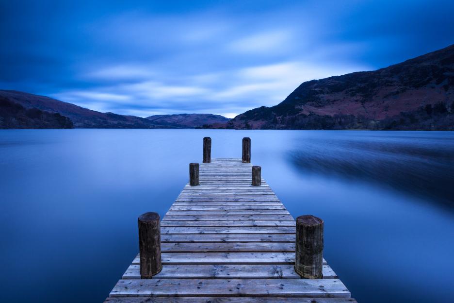 Wooden pier extending into Ullswater lake at dawn.