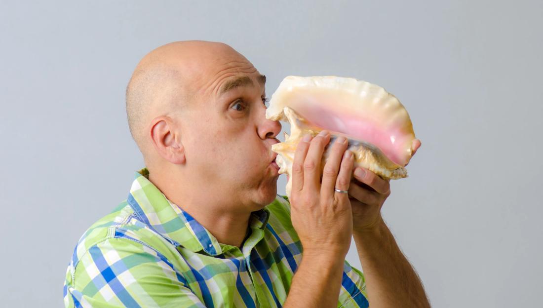 Man blowing a conch shell.