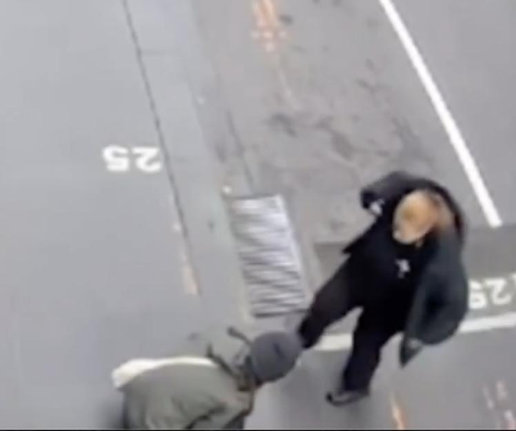 An overhead image of a person in black kicking another person crouched on the ground.