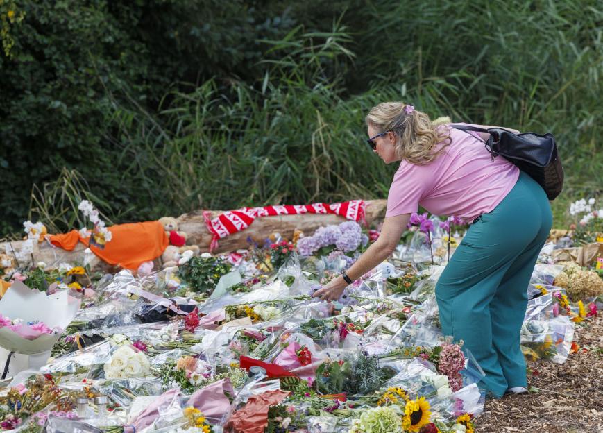 Woman adding flowers to a large memorial.