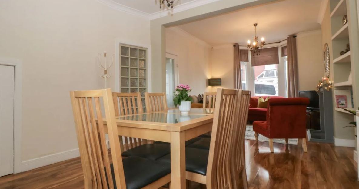 Dining room with a wooden table, six chairs, and a pink floral centerpiece.