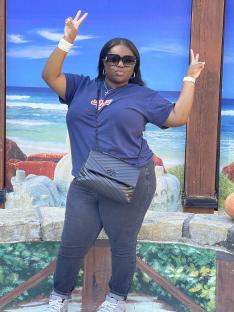 Woman giving peace signs in front of a beach mural.
