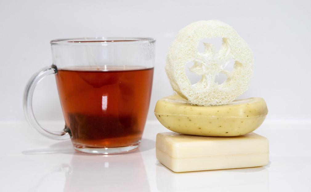 A glass of tea with two stacked bars of soap and a loofah.