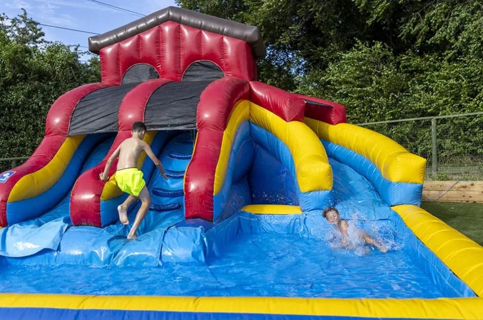 Two children playing on an inflatable water slide.