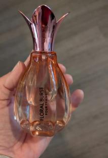 Hand holding a bottle of Floral Burst Pour Femme perfume.