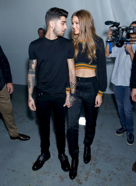 Zayn Malik and Gigi Hadid holding hands at a fashion show.