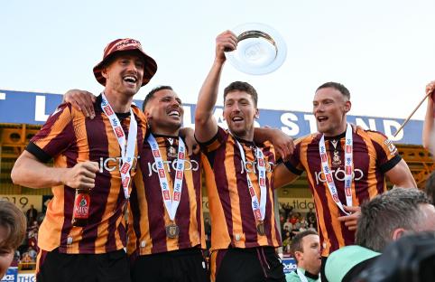 Bradford City players celebrating promotion, holding a trophy.
