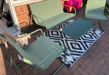 Dog resting near a green patio set.