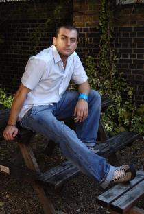 Photo of Paul Danan sitting on a park bench.