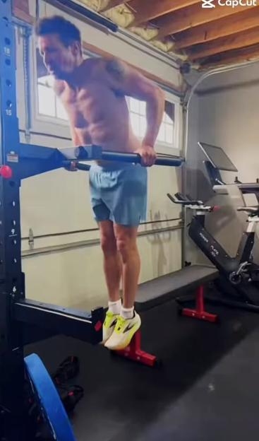 Man performing L-sit exercise on gym equipment.