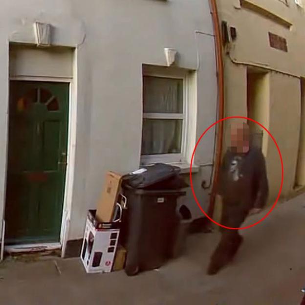Video still of a man defecating on a doorstep.