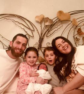 Family photo of parents and three children, including a newborn baby.