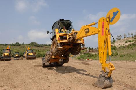 A yellow JCB excavator performing stunts at Diggerland.