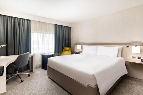Hotel king bedroom with a large bed, desk, and chair.