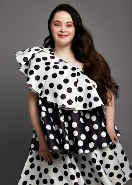 Portrait of a smiling woman wearing a black and white polka dot dress.