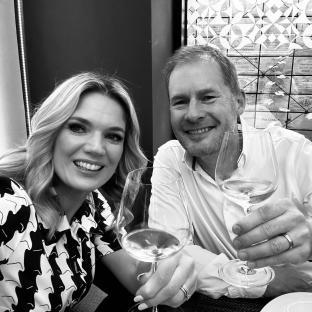 Black and white photo of a couple toasting with wine glasses.