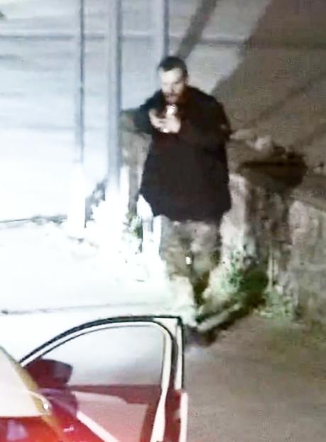 Low-quality CCTV image of Jacob Jenkins brandishing a gun at a police officer.