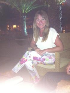Woman sitting outdoors at night wearing floral pants.