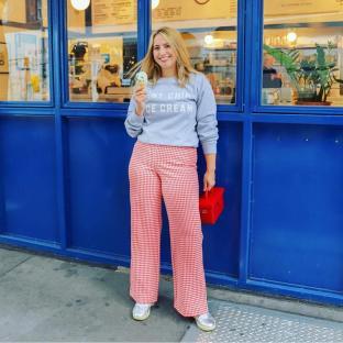 Woman in gingham pants holding ice cream cone.