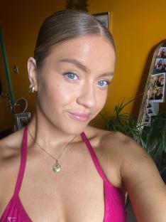 Woman in pink swimsuit top wearing a gold necklace.
