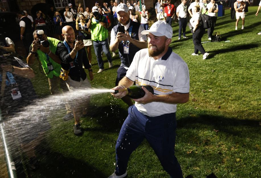 Shane Lowry spraying champagne from a bottle during Ryder Cup celebrations.