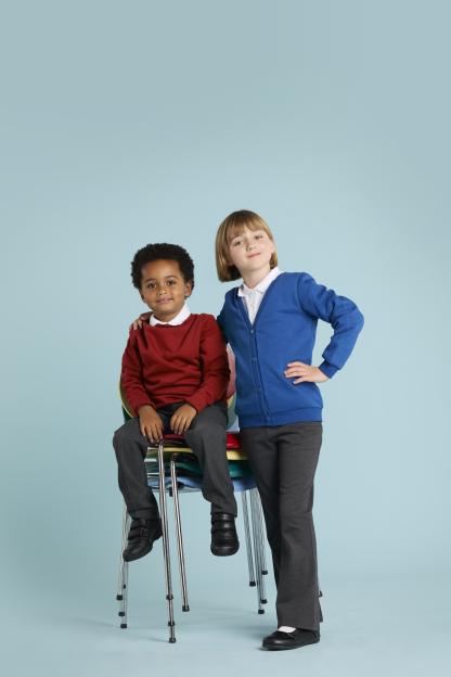 Two schoolchildren, one sitting on a stack of chairs, the other standing behind.
