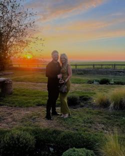 Couple standing in a field at sunset.