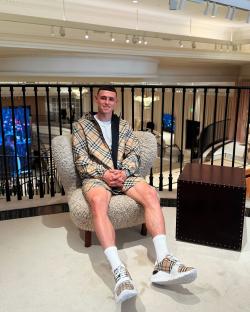 Phil Foden sitting in a chair at a Burberry store.