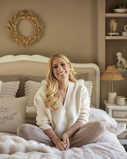 Woman sitting on bed smiling.