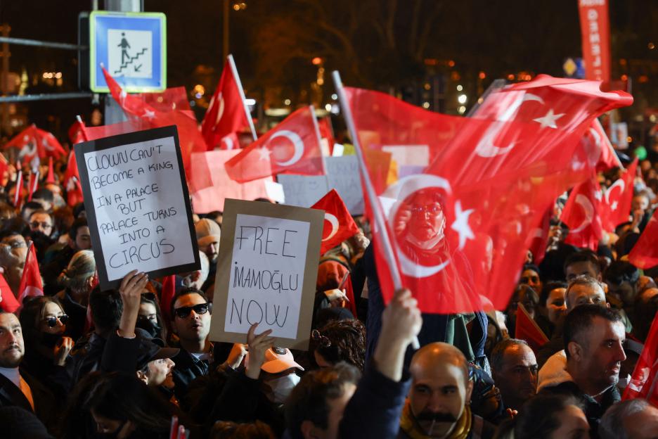 Protestors holding signs that read "Clown can't become a king in a palace but palace turns into a circus" and "Free Imamoglu Now."