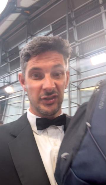 Man in tuxedo speaking to camera.