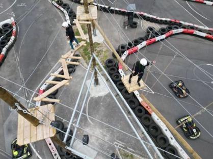 Aerial view of an adventure park high ropes course above a go-kart track.