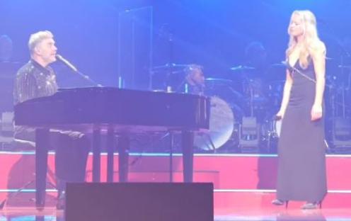 A man playing piano and a woman singing on stage.