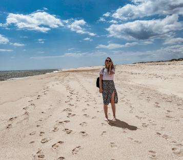 Woman walking on a sandy beach in Algarve, Portugal.